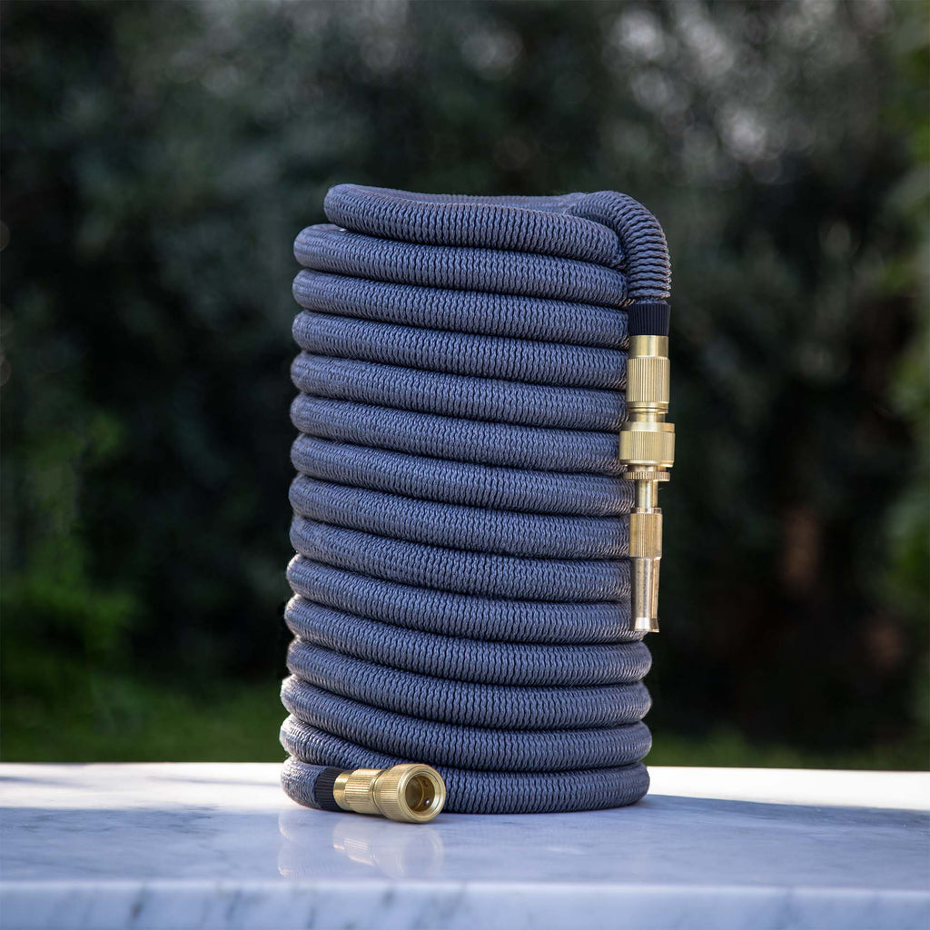 Fritz Tango Soft Expandable Garden Hose in charcoal, perfectly coiled on a marble surface with premium brass fittings. Lightweight, durable, and kink-free for effortless garden care.