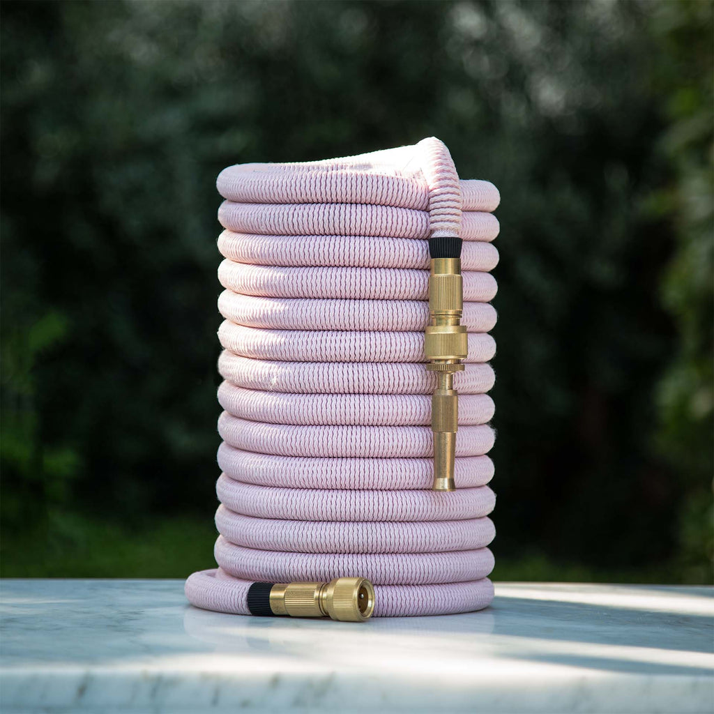 Fritz Tango Soft Expandable Garden Hose in pink, elegantly coiled on a marble surface, featuring premium brass fittings. Lightweight, durable, and kink-free for hassle-free gardening.