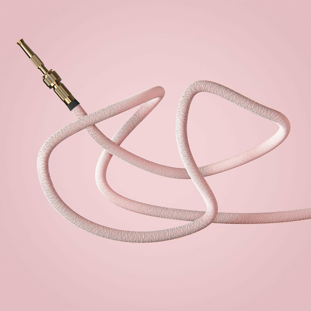 Fritz Tango Soft Expandable Garden Hose in pink, elegantly coiled against a soft pink background. Designed for flexibility and durability, featuring premium brass fittings for stylish and efficient gardening.